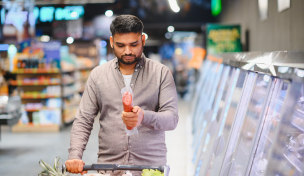 Verbraucher im Supermarkt schaut Wurstverpackung an Verbraucher im Supermarkt schaut Wurstverpackung an