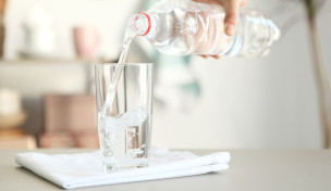 Glas Mineralwasser auf Tisch mit Flasche