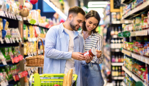 Paar im Supermarkt schaut sich die Rückseite eines Lebensmittels an Paar im Supermarkt schaut sich die Rückseite eines Lebensmittels an
