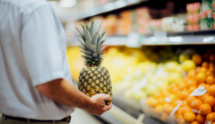 Mann hält eine Ananas im Supermarkt Mann hält eine Ananas im Supermarkt