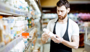 Mann liest Etikett einer Salatsoße Mann liest Etikett einer Salatsoße