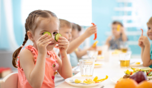 Kind sitzt an einem Tisch und isst Kind sitzt an einem Tisch und isst