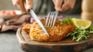 Schnitzel wird mit Besteck angeschnitten Schnitzel wird mit Besteck angeschnitten