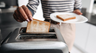 Frau nimmt Scheibe aus Toaster Frau nimmt Scheibe aus Toaster