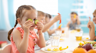 Kind sitzt an einem Tisch und isst Kind sitzt an einem Tisch und isst