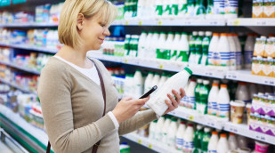 Frau mit Handy-Shopping Milch in Lebensmittelgeschäft